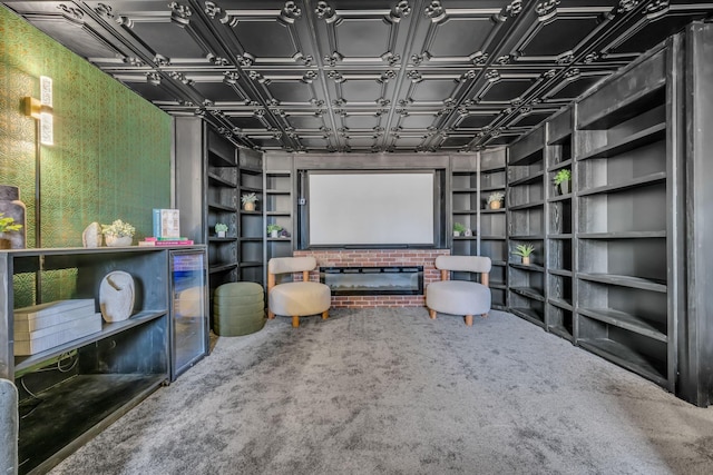 home theater room with a brick fireplace, built in shelves, and carpet flooring