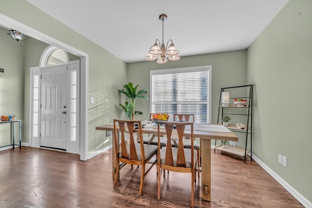 dining area featuring dark wood-type flooring and an inviting chandelier