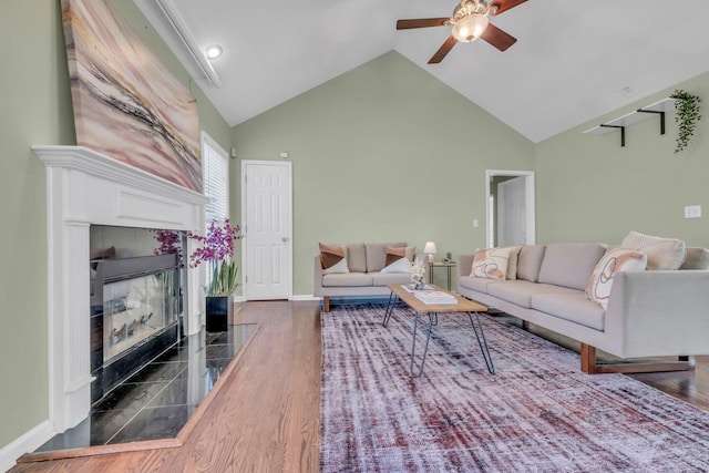 living room featuring ceiling fan, a tile fireplace, high vaulted ceiling, and wood-type flooring