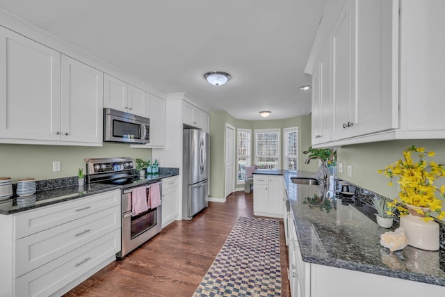 kitchen with sink, dark stone counters, appliances with stainless steel finishes, and white cabinetry