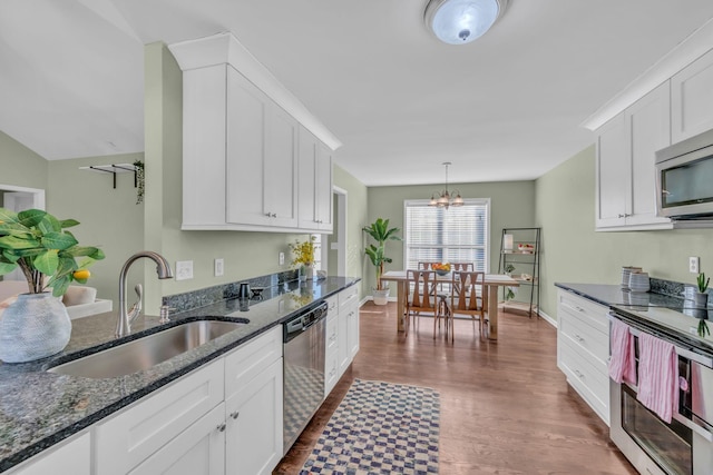 kitchen with stainless steel appliances, white cabinetry, sink, and an inviting chandelier