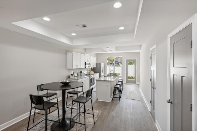 dining area featuring sink, dark wood-type flooring, and a tray ceiling