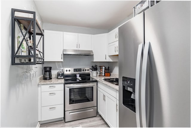 kitchen with appliances with stainless steel finishes, light wood-type flooring, white cabinets, and light stone counters