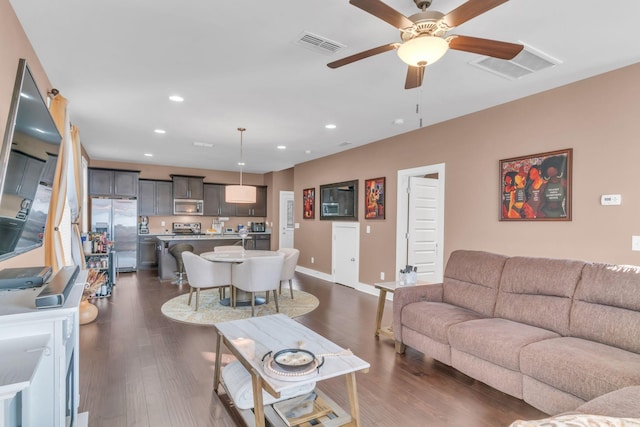 living room featuring ceiling fan and dark hardwood / wood-style floors