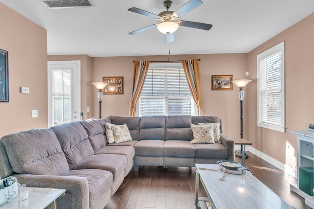 living room with ceiling fan and dark wood-type flooring