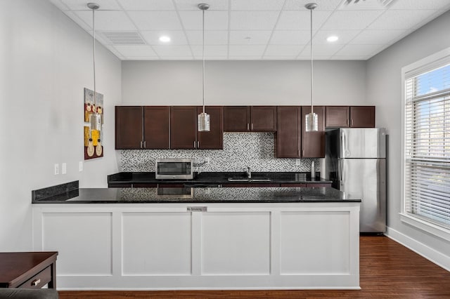 kitchen with dark brown cabinetry, dark wood-style floors, appliances with stainless steel finishes, backsplash, and a sink