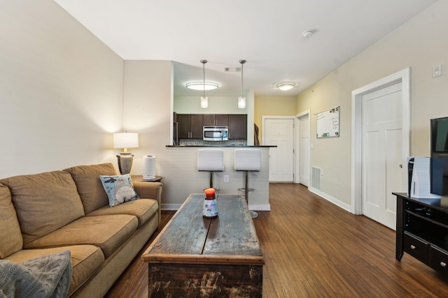 living area with baseboards, visible vents, and dark wood finished floors