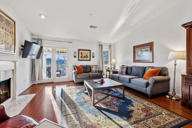 living room featuring dark wood-type flooring, plenty of natural light, a fireplace, and vaulted ceiling