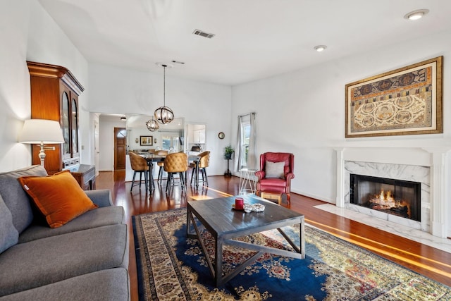 living room with dark hardwood / wood-style floors, a notable chandelier, and a high end fireplace