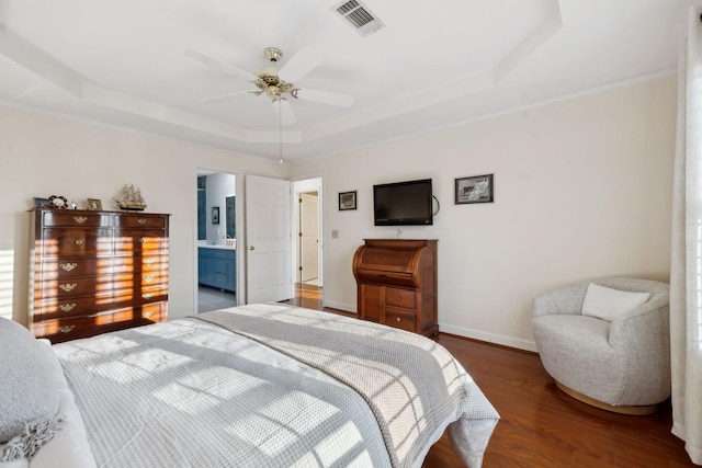 bedroom with ceiling fan, connected bathroom, dark hardwood / wood-style floors, and a raised ceiling