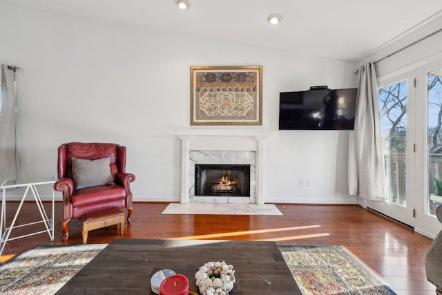 living room with a premium fireplace, lofted ceiling, and dark wood-type flooring