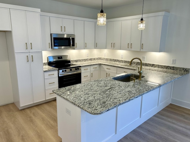 kitchen featuring white cabinetry, appliances with stainless steel finishes, sink, light hardwood / wood-style flooring, and decorative light fixtures