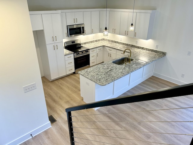 kitchen featuring kitchen peninsula, decorative light fixtures, stainless steel appliances, white cabinetry, and sink