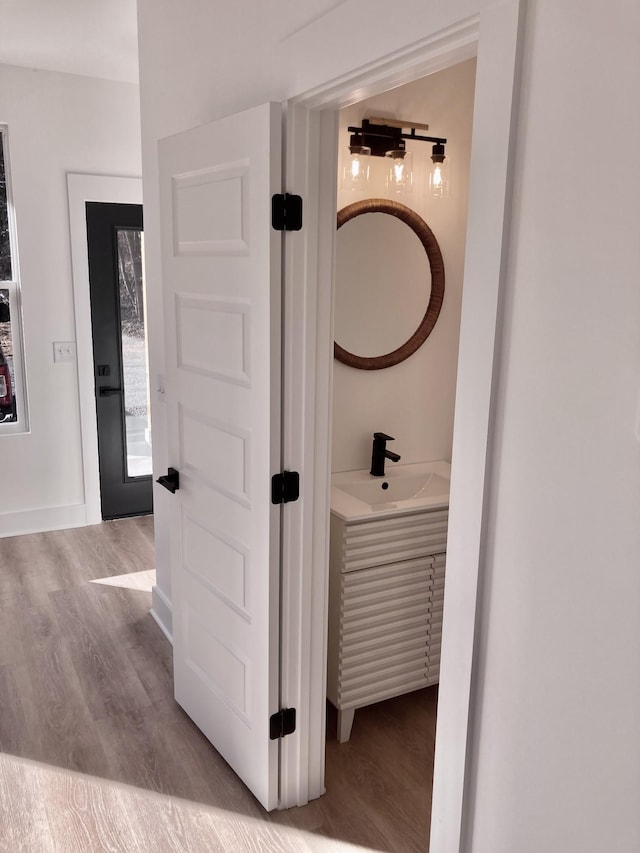 corridor with sink and light wood-type flooring