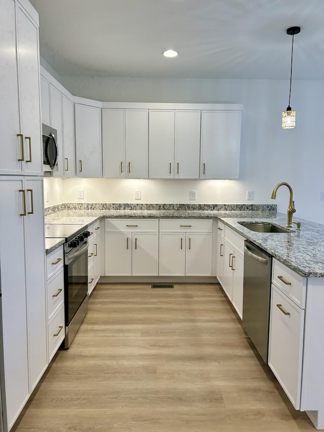 kitchen with stainless steel appliances, white cabinets, pendant lighting, and sink