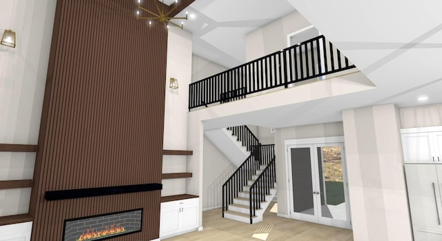 staircase featuring a high ceiling, wood-type flooring, and a large fireplace