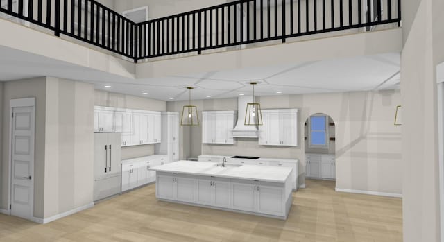 kitchen featuring a kitchen island with sink, hanging light fixtures, a high ceiling, white cabinets, and custom exhaust hood