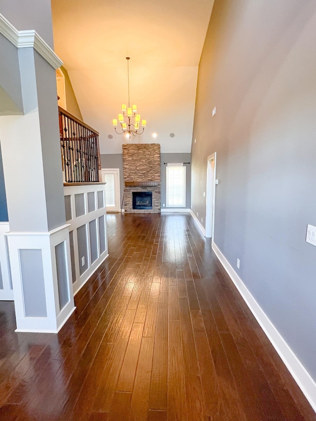 unfurnished living room with a notable chandelier, dark hardwood / wood-style flooring, a fireplace, and a high ceiling