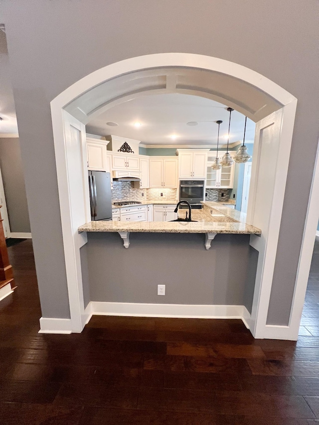 kitchen with stainless steel appliances, hanging light fixtures, premium range hood, decorative backsplash, and white cabinets