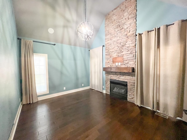 unfurnished living room with high vaulted ceiling, dark hardwood / wood-style floors, a notable chandelier, and a stone fireplace