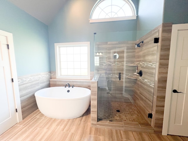 bathroom with lofted ceiling, tile walls, and independent shower and bath