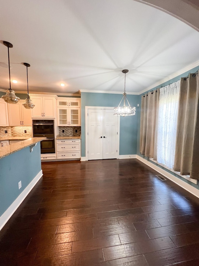 interior space with dark wood-type flooring, ornamental molding, and a chandelier