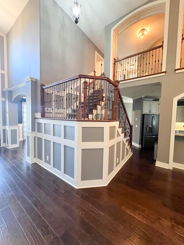 staircase featuring a high ceiling and wood-type flooring