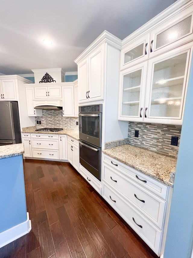 kitchen with appliances with stainless steel finishes, custom range hood, dark hardwood / wood-style flooring, decorative backsplash, and white cabinetry