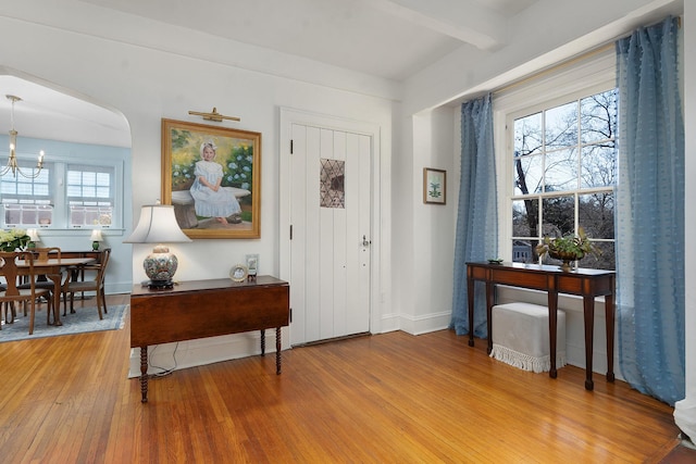 foyer featuring hardwood / wood-style floors, beam ceiling, and an inviting chandelier