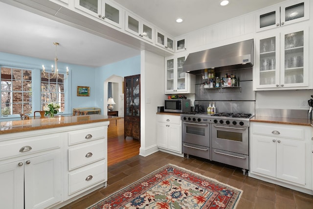 kitchen featuring decorative light fixtures, a notable chandelier, extractor fan, appliances with stainless steel finishes, and white cabinets