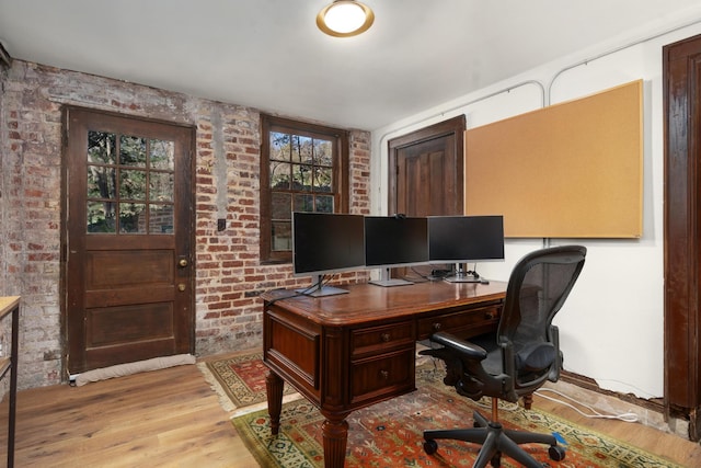 office area with brick wall and light wood-type flooring