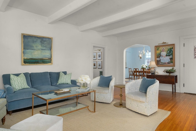 living room featuring beamed ceiling, an inviting chandelier, and hardwood / wood-style floors