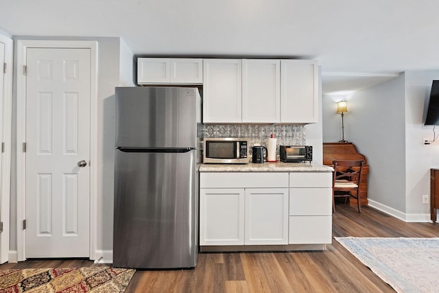 kitchen with light hardwood / wood-style floors, stainless steel appliances, white cabinetry, and tasteful backsplash