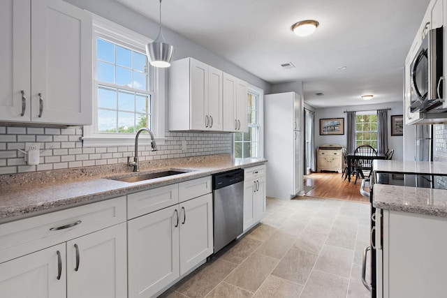 kitchen with stainless steel appliances, pendant lighting, sink, white cabinetry, and tasteful backsplash