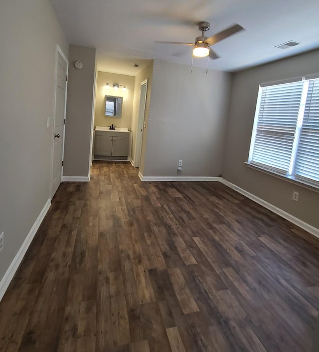 interior space featuring ceiling fan, ensuite bathroom, dark hardwood / wood-style flooring, and sink