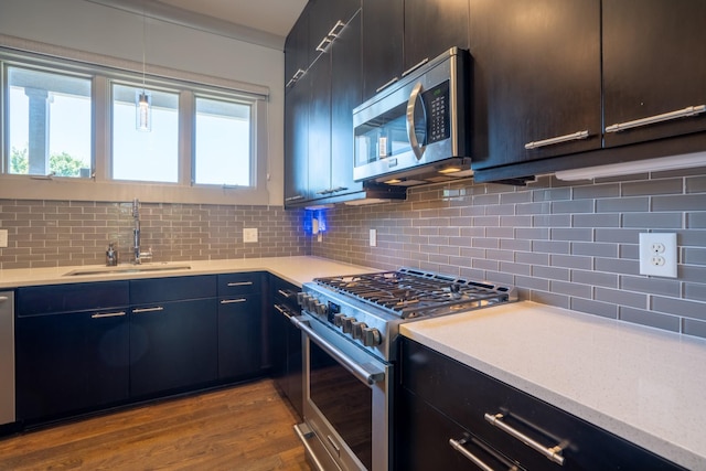 kitchen with decorative light fixtures, stainless steel appliances, light hardwood / wood-style floors, tasteful backsplash, and sink