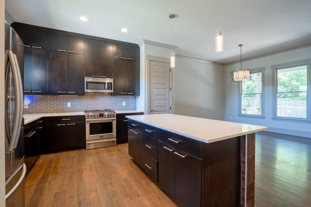 kitchen featuring a center island, hanging light fixtures, stainless steel appliances, tasteful backsplash, and light wood-type flooring