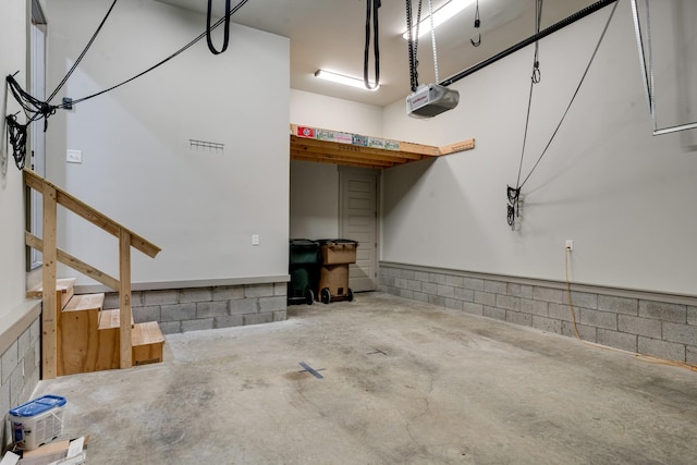 garage featuring concrete block wall and a garage door opener