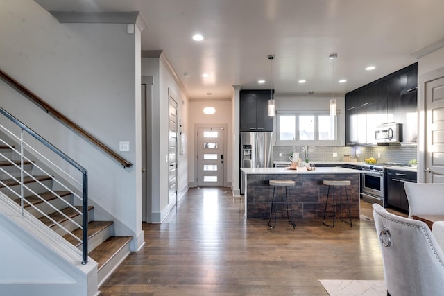 kitchen featuring light countertops, backsplash, appliances with stainless steel finishes, a kitchen island, and a kitchen breakfast bar