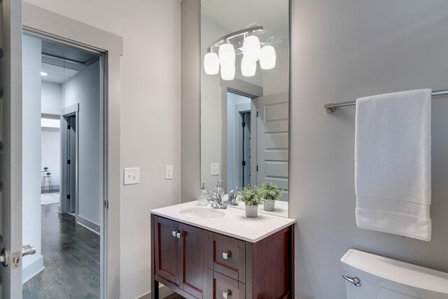 bathroom with toilet, baseboards, wood finished floors, and vanity