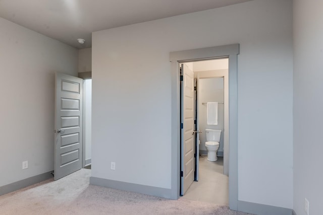 bedroom featuring ensuite bath, carpet flooring, and baseboards