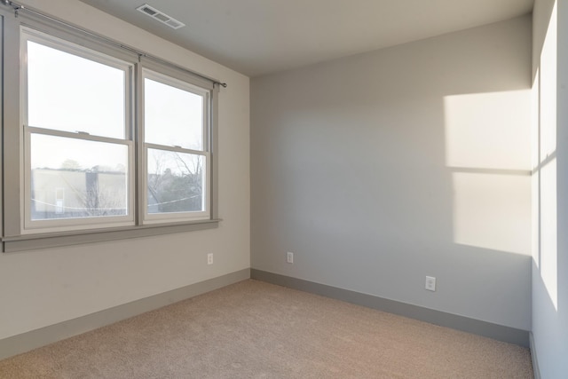 empty room with visible vents, light carpet, and baseboards