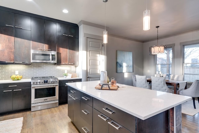 kitchen featuring appliances with stainless steel finishes, light countertops, backsplash, and light wood finished floors