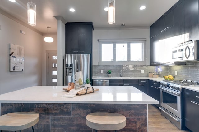 kitchen with light countertops, appliances with stainless steel finishes, a breakfast bar area, and a sink