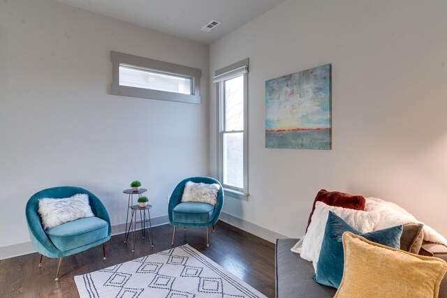 living area featuring visible vents, baseboards, and wood finished floors