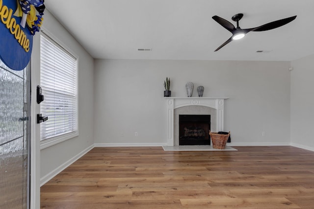 unfurnished living room featuring a fireplace, light wood-type flooring, and ceiling fan