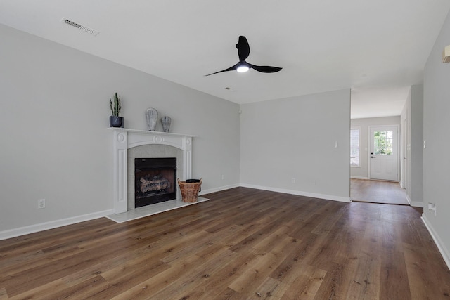 unfurnished living room with a tile fireplace, ceiling fan, and dark hardwood / wood-style floors