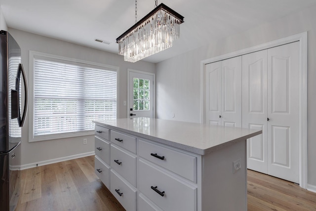 spacious closet featuring light wood-type flooring and a notable chandelier