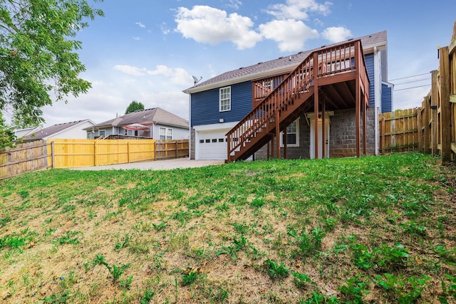 back of property with a yard, a wooden deck, and a garage