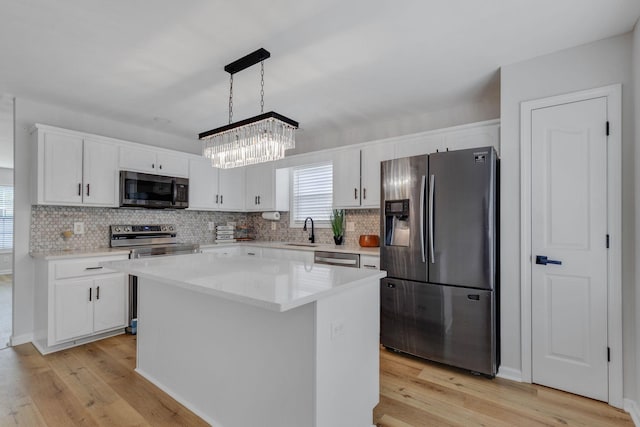 kitchen with a center island, decorative light fixtures, an inviting chandelier, white cabinetry, and appliances with stainless steel finishes